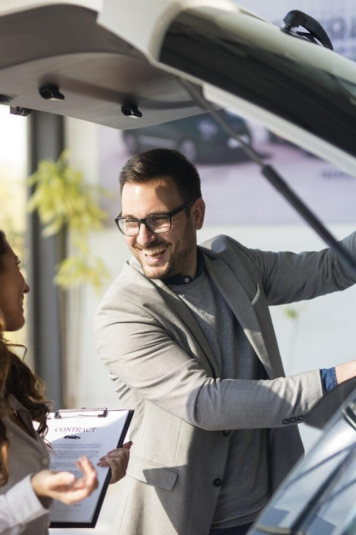 1760536954_car-buyer-testing-trunk-space-new-car-local-vehicle-dealership-showroom